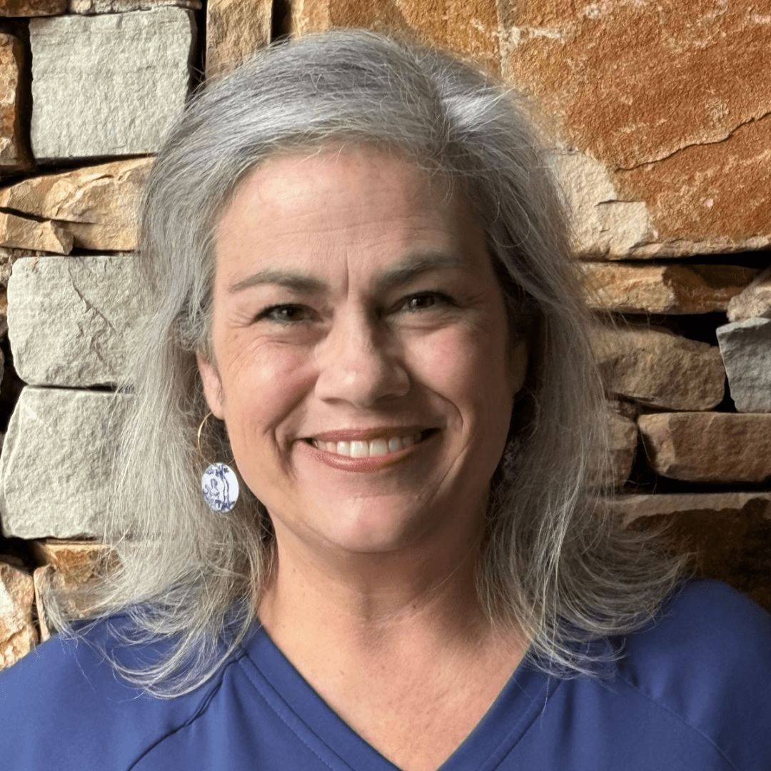 Smiling woman with gray hair in front of a stone wall. Smiling woman with gray hair in front of a stone wall.