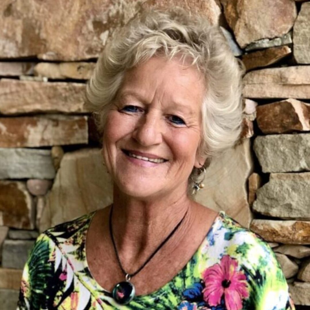 Smiling elderly woman with short white hair in front of a stone wall. Smiling elderly woman with short white hair in front of a stone wall.